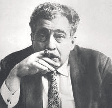 Retrato en blanco y negro de un hombre mayor con cabello canoso y barba, sosteniendo un cigarro con una mano, mientras mira hacia la cámara.