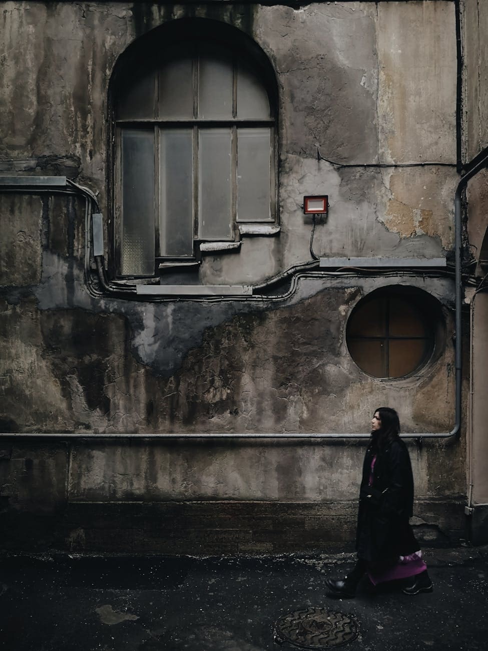 woman in black coat standing in front of window