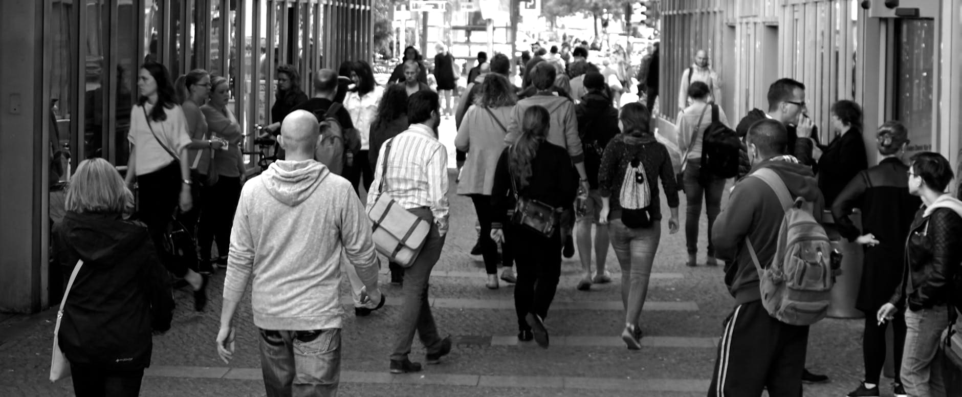 grayscale photography of people walking near buildings